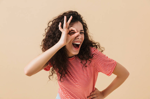 Photo of happy emotional young woman isolated over beige wall background showing okay gesture. - Φωτογραφία, εικόνα
