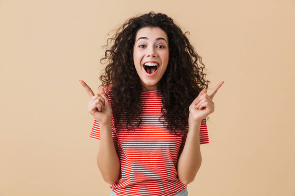 Photo of excited emotional young woman isolated over beige wall background showing copyspace. - 写真・画像
