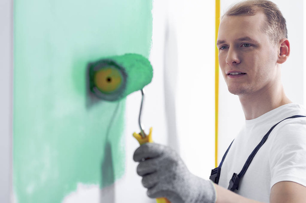 Close-up of a painter painting a wall green with a roller - Fotó, kép
