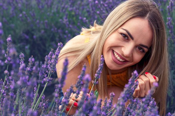 Young smiling woman in lavender field on beautiful summer day - Photo, Image