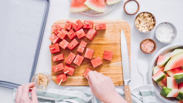 Wassermelone in Würfel schneiden, um mit Schokolade überzogene Wassermelonenbisse zuzubereiten. - Foto, Bild