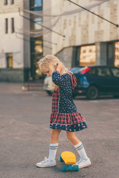 vista lateral de pequena criança adorável andando de skate na rua urbana
 - Foto, Imagem