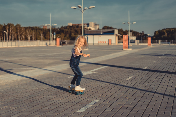 happy little child riding on skateboard at parking lot  - Photo, Image