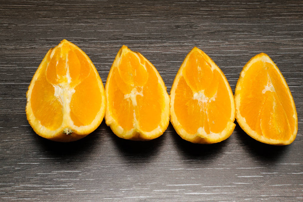 オレンジ色の果物。黒い木の 4 つのオレンジ スライスと部分分離します。. - 写真・画像