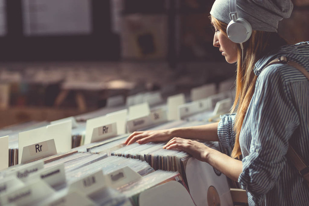 Молодая привлекательная женщина с наушниками в музыкальном магазине
 - Фото, изображение