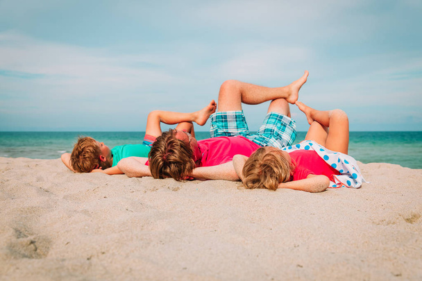 батько з маленьким сином і дочкою розслабляються грати на пляжі
 - Фото, зображення