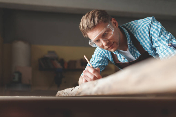 Young man with glasses in the carpentry - Фото, изображение