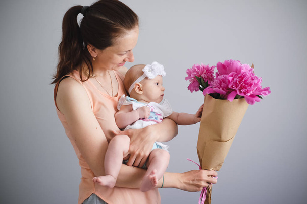 Happy young family. Mother and her daughter glad of flowers bouquet - Fotografie, Obrázek