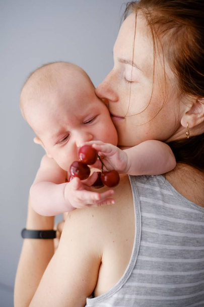 Tenderness and love. Newborn baby with mother explore the world and try fruits - Photo, Image
