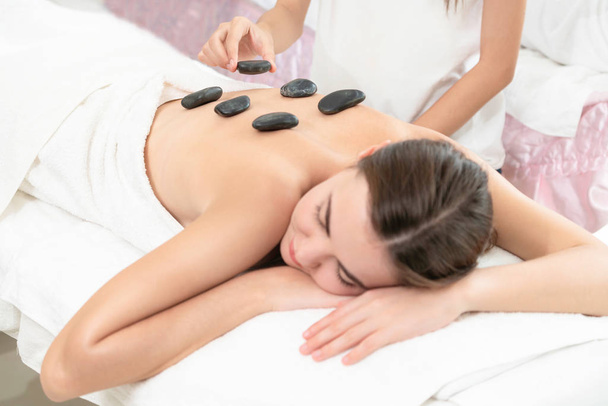 Nő kap forró kő masszázs kezelés professzionális kozmetikus terapeuta a spa szalonban. Luxus wellness, hátfájás és fiatalító koncepció. - Fotó, kép