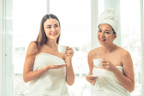 Две женщины пьют чай или травяные напитки во время разговора в роскошном спа-салоне. Концепция здорового образа жизни, отдыха и здоровья
. - Фото, изображение