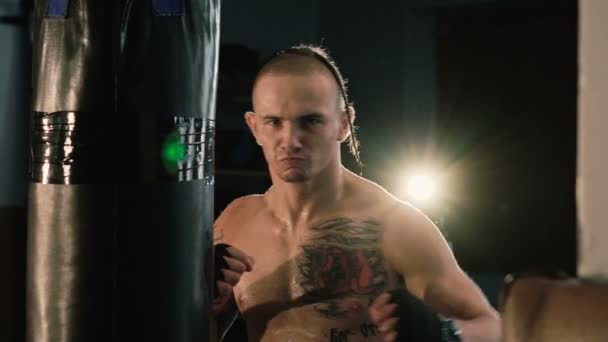 Hairless with pigtail on a head and tattoos, free fighter training punching bag. - Πλάνα, βίντεο