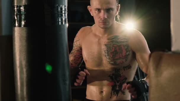 Hairless with pigtail on a head and tattoos, free fighter training punching bag. - Záběry, video