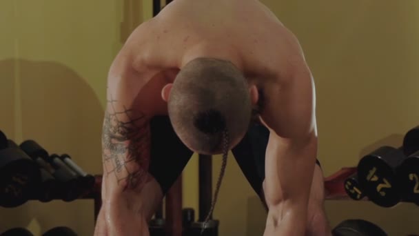 Haarlos mit Tätowierungen hebt der Freikämpfer die harten Hanteln im Fitnessstudio. langsam - Filmmaterial, Video