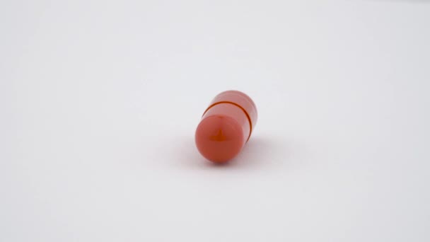 One hard starch capsule rotates on the turn table. Orange color. Isolated on white background. Close up macro. - Video