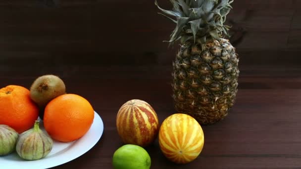 Vegetarian diet. On a white plate are Vietnamese melon, figs, oranges, pineapple. Hd shot with dolly from right to left - Кадри, відео