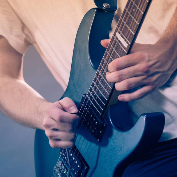 Gros plan de l'homme jouant de la guitare électrique pendant le concert ou au studio de musique. Instruments de musique, passion et concept de passe-temps. - Photo, image