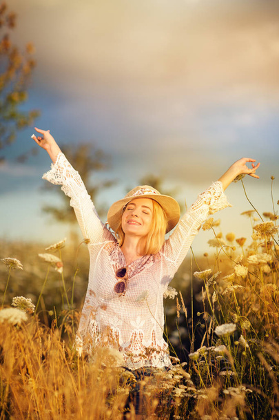 Belle femme dans un pré fleuri avec chapeau de soleil et lunettes de soleil, soif de vie, été, humeur d'automne
 - Photo, image