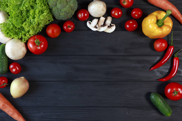Pose plate de différents légumes sur un bureau noir. Vue du haut sur tomates, laitue, poivron, brocoli, oignon, concombre, champignons, champignons, carottes, piments
. - Photo, image