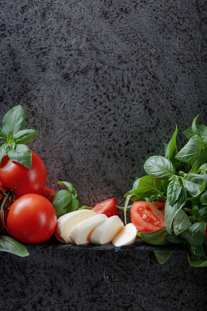Mozzarella con albahaca y tomates sobre un fondo de antigua pared gris. Copia espacio para tu texto
. - Foto, Imagen