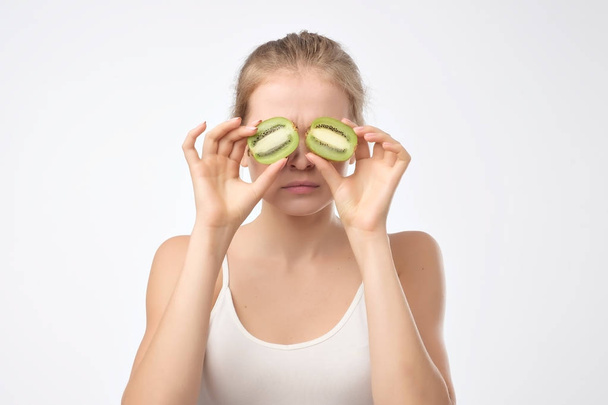 Kiwi. Donna divertente frutta sana che tiene kiwi frutta per gli occhi. Triste emozione facciale
 - Foto, immagini
