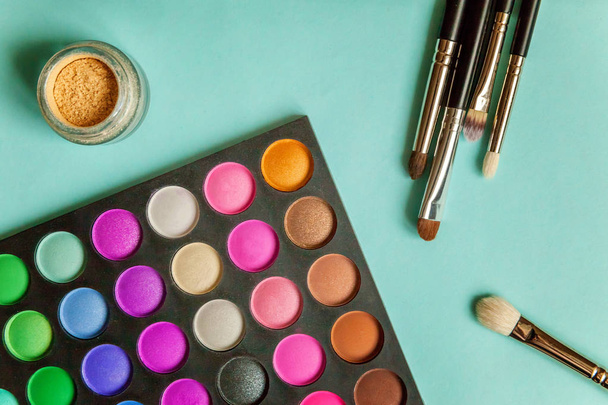 Hulpmiddelen voor make-up en cosmetische producten verschillende tinten oogschaduw op blauwe achtergrond - Foto, afbeelding