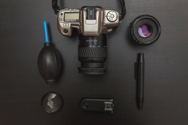 верхний вид рабочего пространства фотограф с системой камеры dslr, комплектом для очистки камеры и аксессуаром для камеры на черном фоне стола
 - Фото, изображение