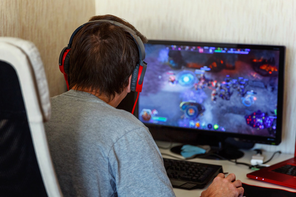 Widok z koncentratu tyłu młodych graczy w słuchawki za pomocą komputera do odtwarzania w domu Gry. Komputer gry konkurencji videogame kontroli konfrontacji koncepcja - Zdjęcie, obraz
