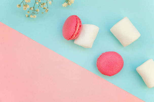 Vue du dessus de mini macaron rose ou macaron gâteau desserts français avec guimauves sur papier doux pastel rose et bleu géométrique fond plat
 - Photo, image