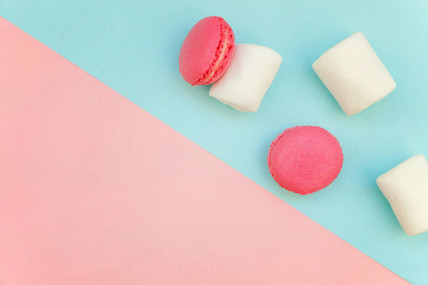 Вид сверху на мини-розовый макарон или макарон на французском десертном торте с зефиром на мягком сладко-розовом и голубом геометрическом плоском фоне
 - Фото, изображение