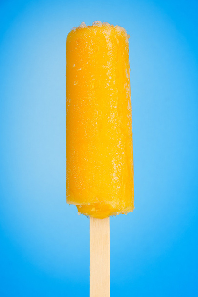 Yellow fruit juice ice on blue background - Foto, Imagen