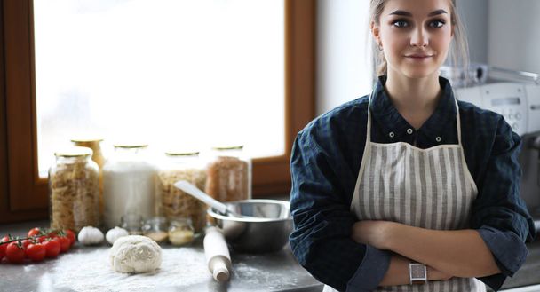 Young woman standing by the stove in the kitchen . - Foto, Bild