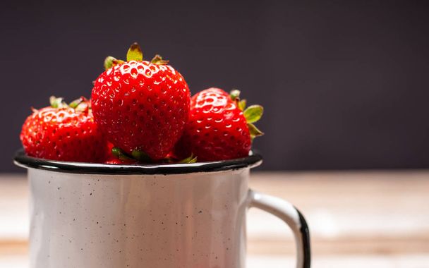 Fresh ripe berry. Strawberries in the cup on wooden table  - Fotografie, Obrázek