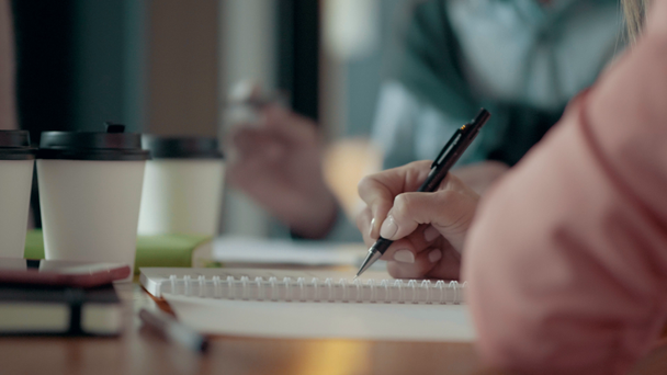 Close-up van handen van Europese vrouw, het maken van notities In Kladblok met Pen op moderne kantoor bureau - Video