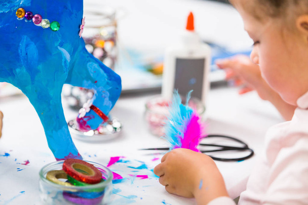 Kislány díszítése festett kék papír mache Egyszarvú. - Fotó, kép
