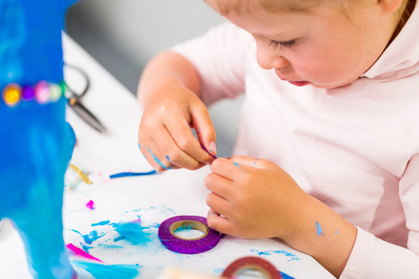 Petite fille décorant peint en papier bleu mache licorne
. - Photo, image