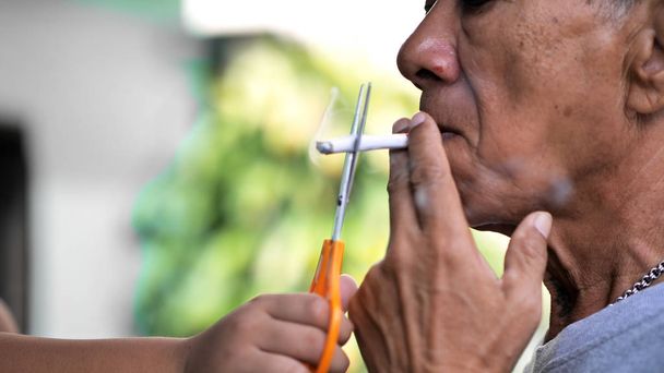 Homem velho está fumando cigarro e as crianças usam tesoura para cortar cigarro. Há muito fumo por aí. Fumar é prejudicial para a sociedade. parar cigarro
 - Foto, Imagem