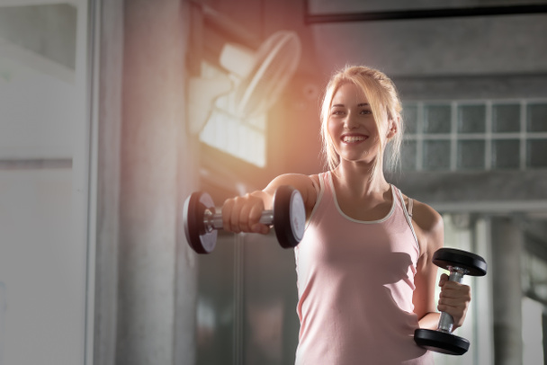 Mujeres jóvenes caucásicas que sonríen felices en un ejercicio con pesas en el gimnasio. Vivir un estilo de vida saludable
. - Foto, Imagen