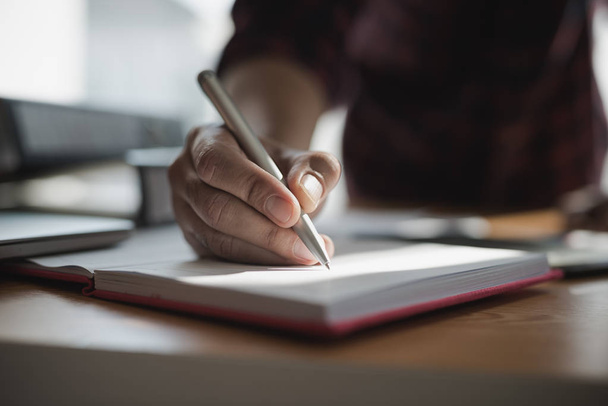 Рука бізнесменів тримає ручку під час написання нотаток у книзі під час зустрічі
. - Фото, зображення
