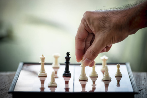 Die Hand eines Geschäftsmannes bewegt Schach auf einem Holzbrett. Spiel, Strategie, Management oder Führung, Geschäftserfolg und Teamwork-Konzept - Foto, Bild