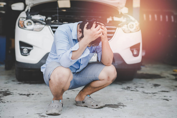 Stres, arabayı tamir maliyeti ile baş ağrısı ile Genç Asyalı adam. - Fotoğraf, Görsel