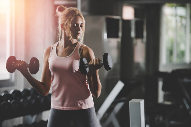 Fiatal nők, akik mosoly boldog gyakorlása során a súlyzó az edzőteremben. Egészséges életmód-életvitel. - Fotó, kép