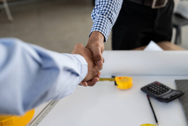 Mühendislik ve iş adamı, ofis merkezinde çalışırken başarılı bir anlaşmadan sonra el sıkışıyor. - Fotoğraf, Görsel