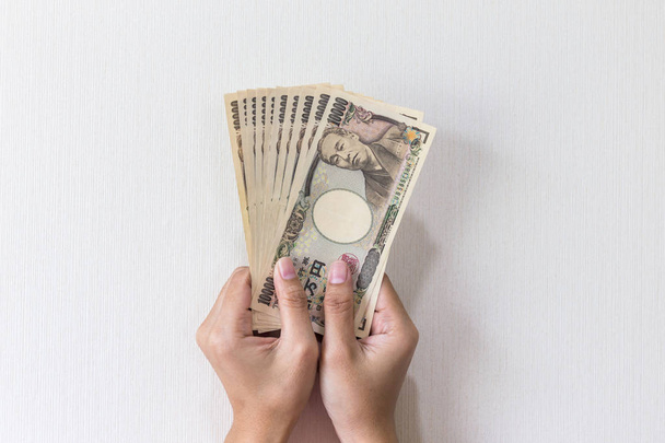 Бізнес-леді даючи гроші і проведення 10000 японської ієни гроші в руці ізольовані на білий фон, Японська ієна фінансової і бізнес-концепції - Фото, зображення