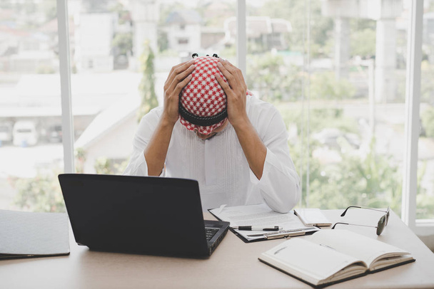 Biznesmen Arab siedzi zestresowany po długich godzinach pracy na laptopie. Koncepcja stresu emocjonalnego, Biznes napięcie - Zdjęcie, obraz