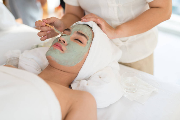Una terapeuta haciendo Facial Spa / Tratamiento Añadir humedad a la piel con la mujer asiática acostada en una cama en el salón de spa
. - Foto, Imagen