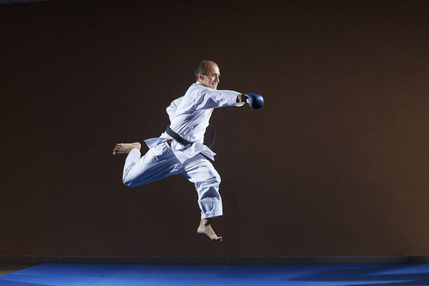 Con sovrapposizioni blu sulle braccia, un atleta allena una mano pugno in salto
 - Foto, immagini