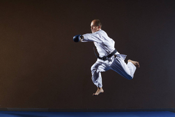 Человек с синими накладками на руках бьет рукой в прыжке
 - Фото, изображение