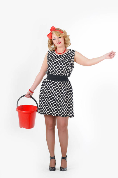 woman blonde in polka-dot dress with red bucket in hands washes floors, housewife - Foto, Bild