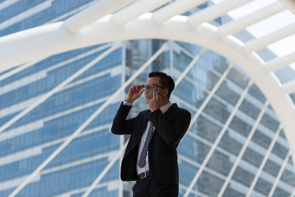 Jonge Aziatische zakenman zweten als gevolg van warm klimaat. Hij veegt het gezicht met natte doekjes, transpiratie, zweet in een stad Bangkok Thailand - Foto, afbeelding